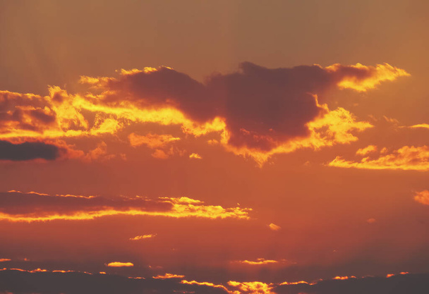 Ein schöner orangefarbener Himmel mit Wolken bei Sonnenuntergang. Natürlicher oranger Hintergrund mit den letzten Sonnenstrahlen des Tages. - Foto, Bild