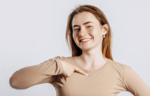 Beautiful young brunette girl smiling and pointing her finger at herself on a white isolated background - Foto, Imagen