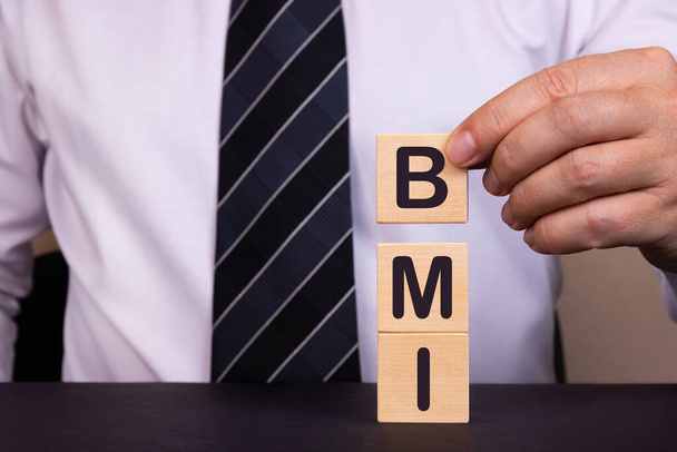 Businessman made word BMI with wood building blocks. - Φωτογραφία, εικόνα