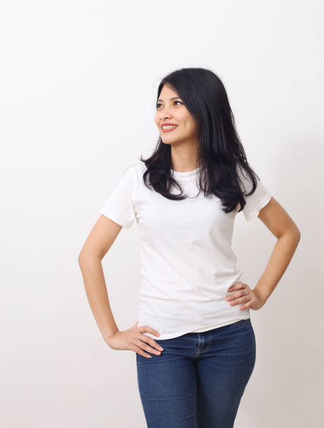 Retrato de hermosa mujer asiática con camisa blanca de pie mientras mira hacia otro lado aislado sobre fondo blanco con copyspace - Foto, Imagen