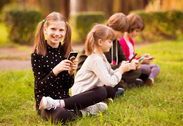 Εκπαίδευση εξ αποστάσεως σε απευθείας σύνδεση. Καυκάσια χαμογελαστά κορίτσια μελετούν με smartphone και κάνουν σχολική εργασία. Σκέψη παιδί κάθεται με το κινητό τηλέφωνο - Φωτογραφία, εικόνα