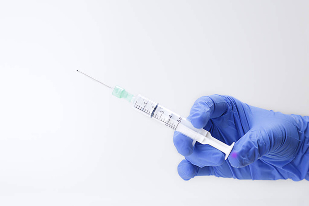 Kéz a kézben orvosi kesztyű fecskendővel. Védőoltás fogalma.  - Fotó, kép