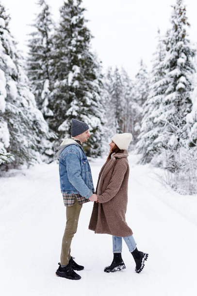 Влюблённые мужчина и женщина смотрят друг на друга в зимнем лесу - Фото, изображение