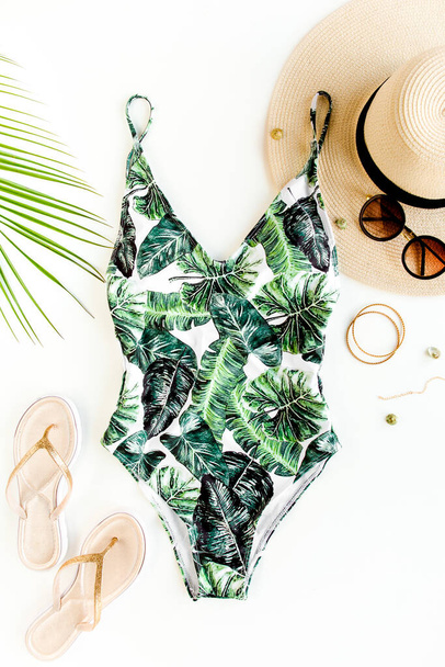 Womans beach accessories: swimsuit with tropical print, straw hat on white background. Summer background.  - Zdjęcie, obraz