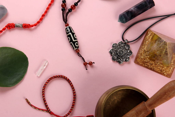 Тибетский бусинка бусинка амулет ожерелье, тибетская чаша пения и другие символы успеха и процветания на розовом фоне - Фото, изображение