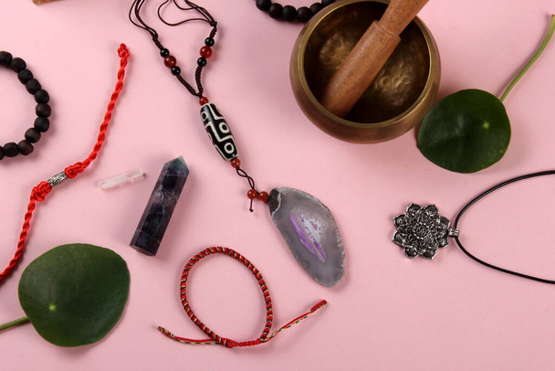 Тибетский бусинка бусинка амулет ожерелье, тибетская чаша пения и другие символы успеха и процветания на розовом фоне - Фото, изображение