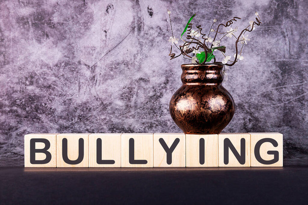 Word BULLYING made with wood building blocks on a gray background - 写真・画像
