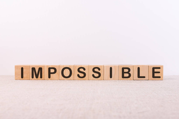 IMPOSSIBLE word concept written on wooden cubes lying on a light table and light background. - Fotoğraf, Görsel