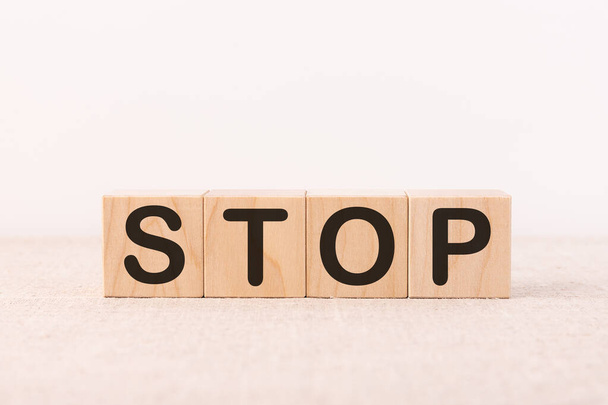 STOP word concept written on wooden cubes blocks lying on a light table and light background - Foto, immagini