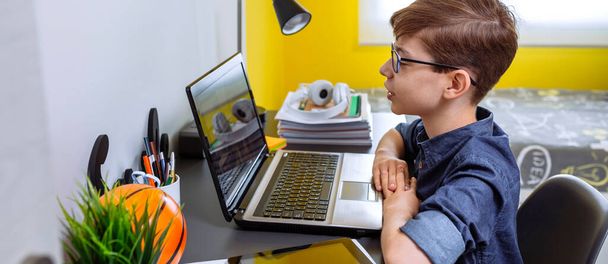 Çocuk, yatak odasındaki dizüstü bilgisayarla evde ders alıyor. - Fotoğraf, Görsel