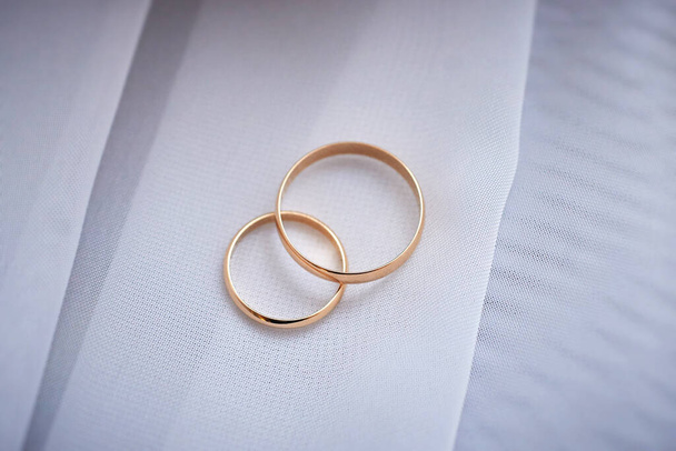 gold wedding rings on a white fabric surface. preparing for the wedding. close-up, macro - Foto, Imagen