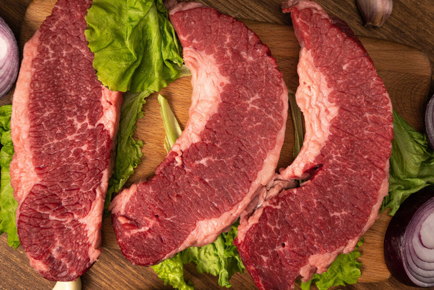 Biftecks de bœuf marbré cru à la laitue, à l'oignon rouge, à l'ail et au concombre. - Photo, image