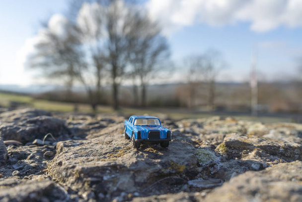 Blaues Modellauto auf einem Felsen in einem Park - Foto, Bild