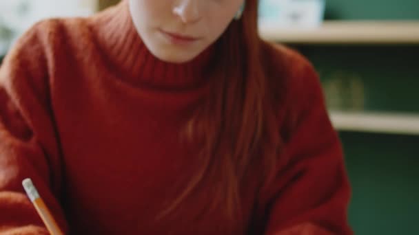 Close-up tiro de jovem mulher de negócios caucasiana escrevendo com lápis no caderno enquanto trabalhava na mesa no escritório - Filmagem, Vídeo