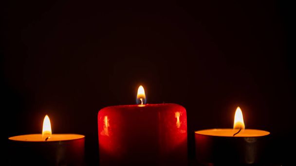 three candles on a black background. close up - Фото, зображення