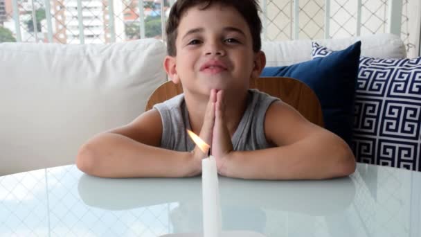 7 year old child praying, laughing and blowing out the candle in front of him. - Footage, Video