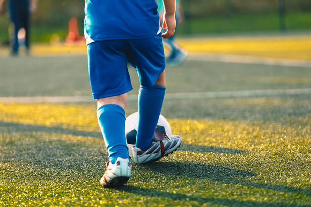 Dítě hraje sport. Děti hrajou fotbal na trávě. Fotbalový trénink v letní slunečný den - Fotografie, Obrázek