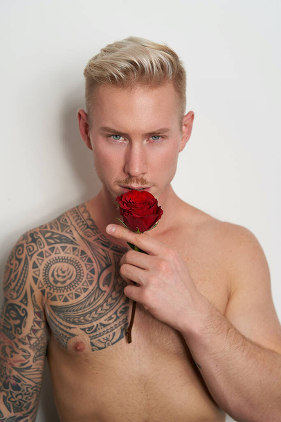 Férfi szerető pózol egy virág / jóképű fiatalember kezében egy vörös rózsa csábító várakozás - Fotó, kép