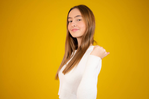 Portrait of a happy young beautiful girl showing okay gesture and winking isolated over yellow background - Фото, зображення