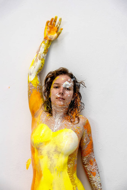 экспрессивная сексуальная верхняя часть брюнетки молодая женщина в желтом и оранжевом цвете, как если бы она носила букет, абстрактная живопись тела - Фото, изображение