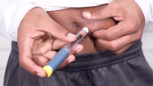 młody człowiek za pomocą wstrzykiwacza insuliny na białej ścianie  - Materiał filmowy, wideo