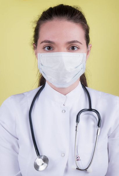 Doctors, infectionist, research and covid19 concept. female doctor receive good results on studying virus, discover vaccine,coronavirus, healthcare and doctors concept. Portrait of young doctor in medical mask, white coat, stethoscope - Фото, изображение