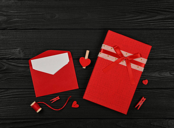 Sevgililer günü hediyeleri, kırmızı kutular, kalpler, sicim, mandallar ve kağıt zarfın içinde siyah ahşap masa arkaplanı, düz yatağı kapat, üst manzaranın hemen üstünde. - Fotoğraf, Görsel