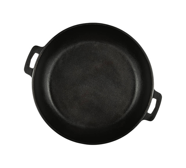 Κλείστε ένα άδειο τηγάνι από μαύρο χυτοσίδηρο που απομονώνεται σε λευκό φόντο, υψωμένη πάνω όψη, ακριβώς από πάνω - Φωτογραφία, εικόνα