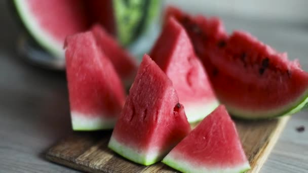 Uzavřete plátky zralého melounu na dřevěné desce v kuchyni. Mňam meloun na dřevěném stole - Záběry, video