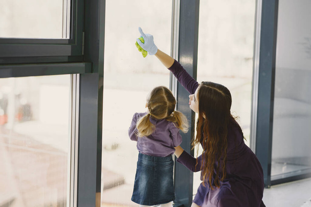 Fille et mère nettoyer la fenêtre ensemble - Photo, image