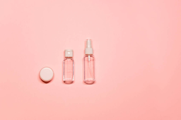 Minimalist layout composition with natural skincare products: lip balm, toner, and facial mist on a light pink background. - Fotó, kép