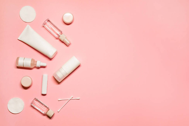 Stylish layout composition on a pink background with cosmetic products: hand cream, facial serum, essential oil, toner, deodorant, lip balm, cotton pads and buds. - Foto, afbeelding