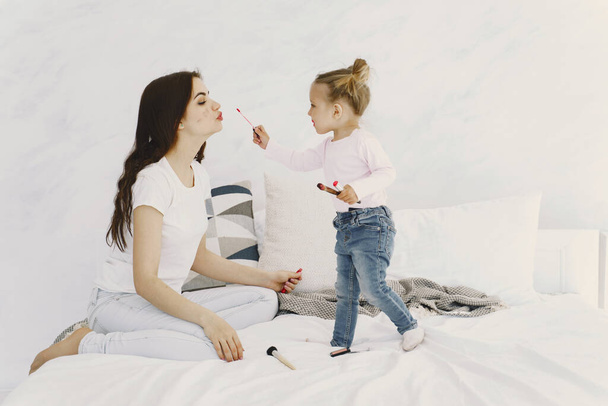 Mom playing with cosmetics in bed with her daughter - Foto, Bild