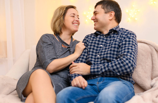 portrait of adult couple sitting on a sofa at home. - Photo, image