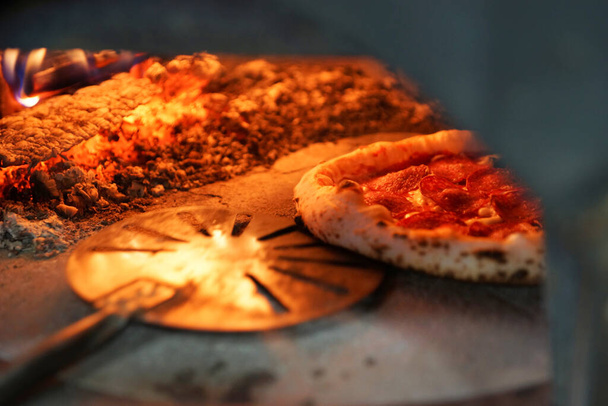 Neapolitan pizza with sausage in a wood-fired oven - Photo, Image