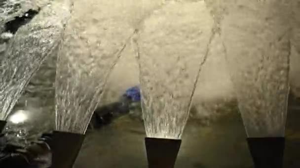 Hitaasti liikkuvan suihkulähteen vesipisarat, joiden tausta on hyvin hämärä - Materiaali, video