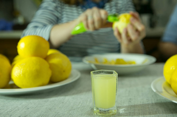 El proceso de hacer licor de limón limoncello en casa. La mujer quita la ralladura de los limones. - Foto, imagen