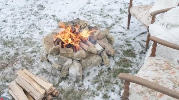 Feuer im Schnee im Winterwald mit den bequemen Sesseln. - Filmmaterial, Video