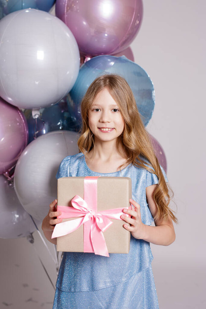 happy girl in studio with air balloons and gift box over white background - Zdjęcie, obraz