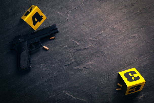 Bullets, gun and crime scene markers on black slate background, flat lay. Space for text - Фото, зображення
