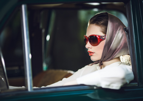 An attractive young woman girl looking at the camera from the front seat of the car - Фото, зображення