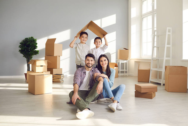 Portrait of smiling mother, father and children in their new house on moving day - 写真・画像