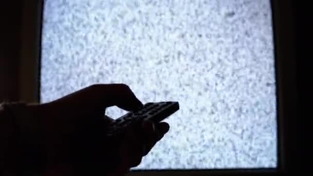 Mężczyzna zmienia kanały z zakłóceniami szumów ekranu w ciemnym pokoju. Retro TV - Materiał filmowy, wideo