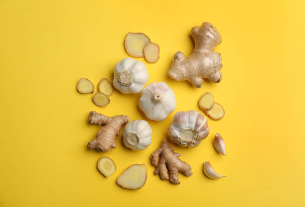 Ginger and garlic on yellow table, flat lay. Natural cold remedies - Photo, Image