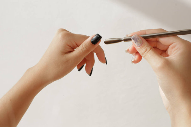 Well-groomed womens hands with interesting manicure hold a tool for manicure - 写真・画像