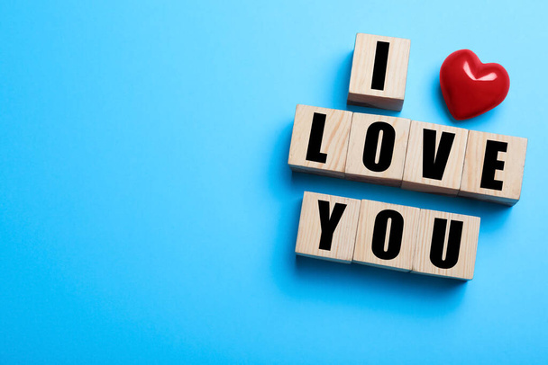 Cubes with words I Love You and red heart on light blue background, flat lay. Space for text - Fotó, kép