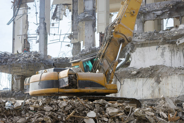 Closeup of special hydraulic excavator-destroyer during operation, ruins of a building on background. Ultra high demolition equipment - Photo, Image