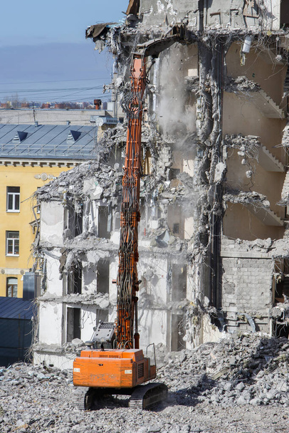 Demolition of building with excavator-destroyer for high-altitude work. Grab crane with hydraulic scissors. Reinforced concrete structures. - Photo, Image