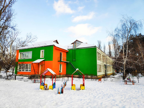 Moderní barevná školka s dětským hřištěm v zimě se sněhem. Architektonický koncept budovy a rozvoje - Fotografie, Obrázek