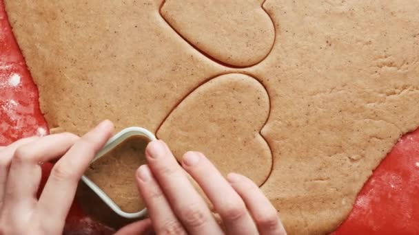 Hacer galletas en forma de corazón para el Día de San Valentín con molde de plástico en la alfombra de silicona roja para hornear.  - Imágenes, Vídeo